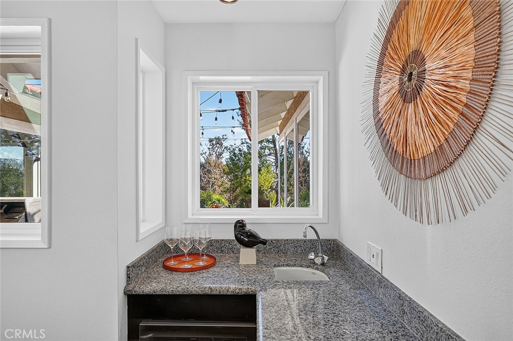 The bar is a couple steps down to a lower level and has a row of cabinets, wine fridge, and a sink - 10571 Morada, Orange CA 92869 - photo 30