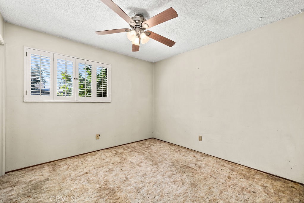 Bedroom features a ceiling fan and dual-pane vinyl window with plantation-style shutters. - 150 S Park, Orange CA 92869 - photo 22