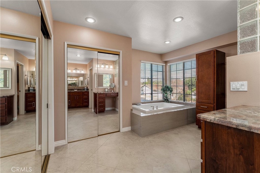 In suite, bathroom consist of granite countertops, soaking tub, mirror, wardrobes, tile floors, and separate toilet room - 390 N Milford Road, Orange CA 92867 - photo 34