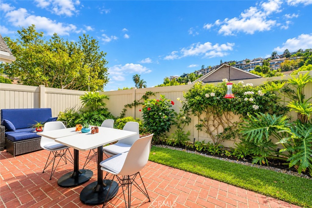 Step outside to your private, landscaped backyard featuring a charming brick patio and an impressive 20' x 10' motorized - 5049 E Almond Avenue 4, Orange CA 92869 - photo 26