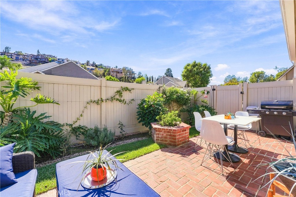 Step outside to your private, landscaped backyard featuring a charming brick patio and an impressive 20' x 10' motorized - 5049 E Almond Avenue 4, Orange CA 92869 - photo 27