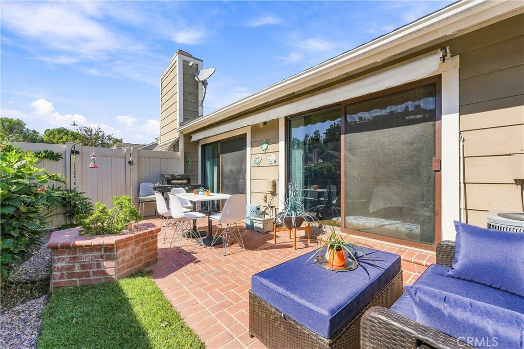 Step outside to your private, landscaped backyard featuring a charming brick patio and an impressive 20' x 10' motorized - 5049 E Almond Avenue 4, Orange CA 92869 - photo 28