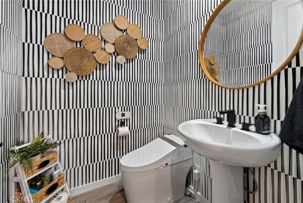 The half bathroom has a bidet and pedestal sink, as well as gorgeous wallpaper and accent fixtures. - 14 Marisol, Rancho Mission Viejo CA 92694 - photo 32