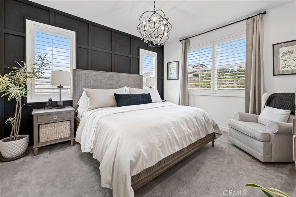 The Primary Bedroom has custom shutters on the dual pane windows, a beautiful chandelier, and an accent wall with wainsc - 14 Marisol, Rancho Mission Viejo CA 92694 - photo 33