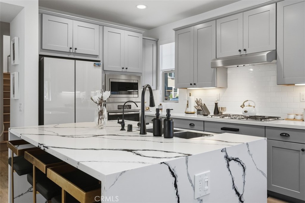 The showstopping marble island offers generous seating and prep space, complemented by a matte black pull-down faucet, s - 33 Lomada Street, Rancho Mission Viejo CA 92694 - photo 7