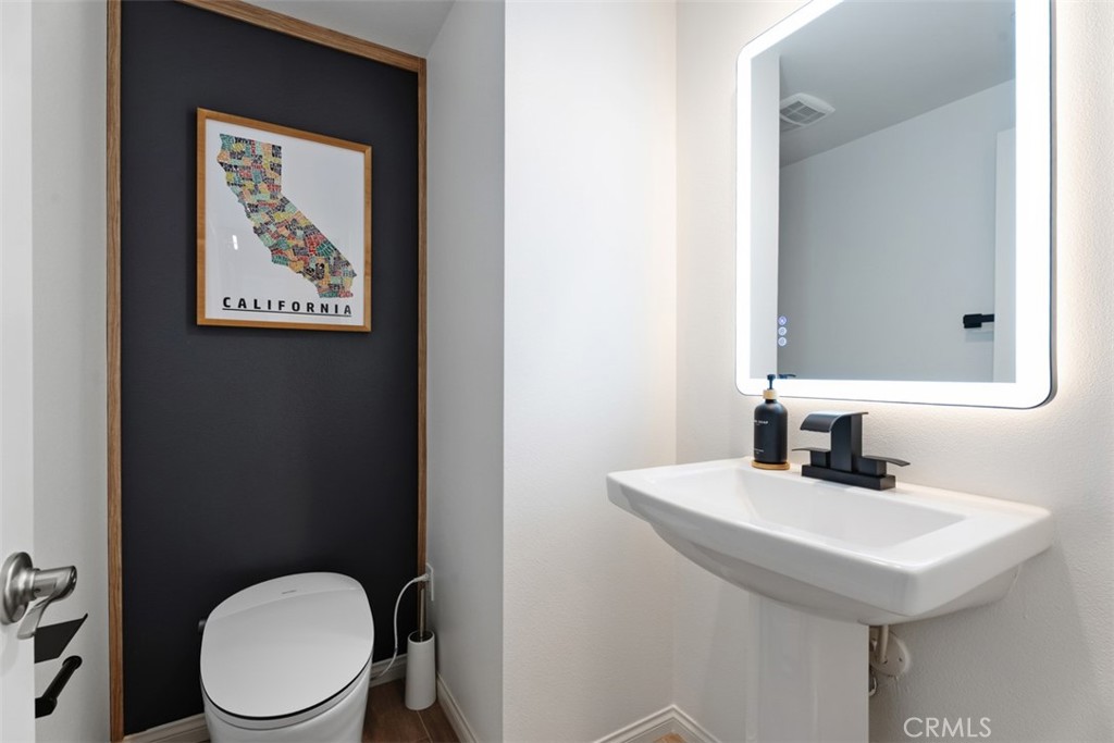 The stylish main-level powder room features a new smart bident toilet, upgraded vanity with matte black fixtures, design - 33 Lomada Street, Rancho Mission Viejo CA 92694 - photo 15