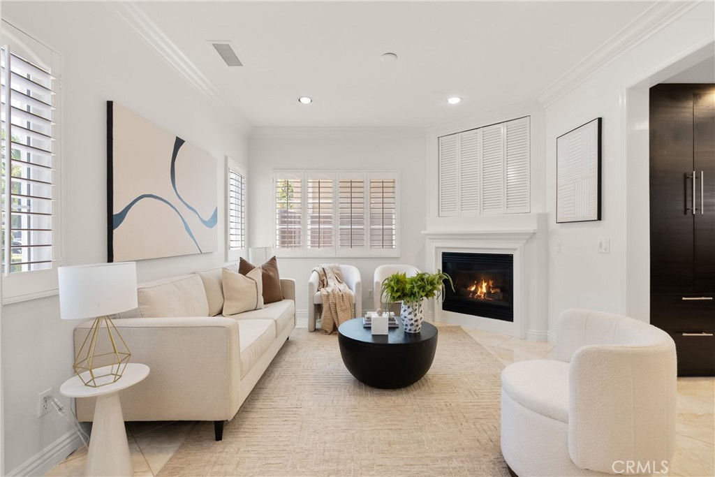 Bright and inviting living room featuring abundant natural light, plantation shutters, a cozy fireplace, and an open flo - 15 Poppyfield, Rancho Santa Margarita CA 92688 - photo 2