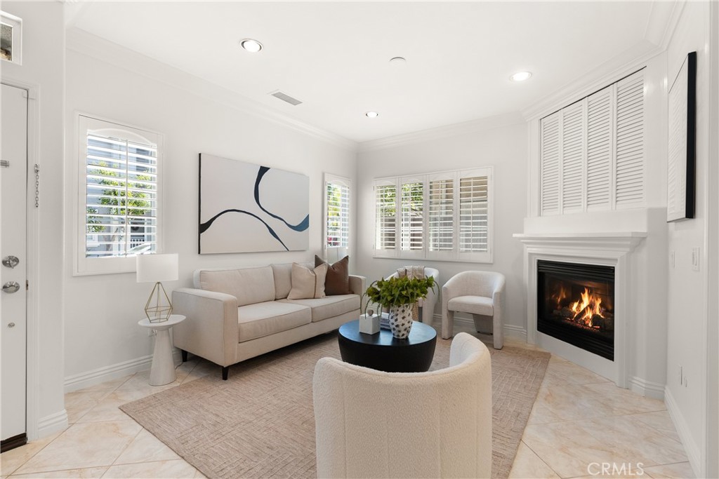Bright and inviting living room featuring plantation shutters, recessed lighting, crown molding, and a cozy fireplace th - 15 Poppyfield, Rancho Santa Margarita CA 92688 - photo 3
