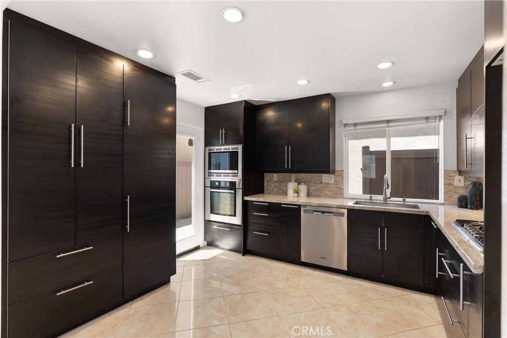 Beautifully remodeled kitchen featuring rich espresso cabinetry, granite countertops, stainless steel appliances, a gas - 15 Poppyfield, Rancho Santa Margarita CA 92688 - photo 7