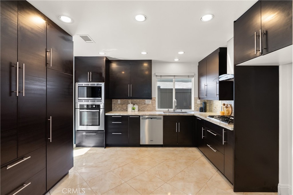 Beautifully remodeled kitchen featuring rich espresso cabinetry, granite countertops, stainless steel appliances, a gas - 15 Poppyfield, Rancho Santa Margarita CA 92688 - photo 8