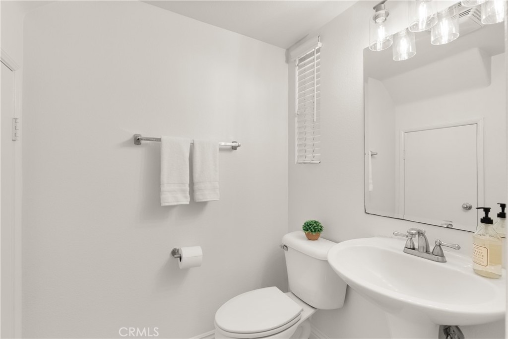 The main level powder room is thoughtfully positioned for guests and features a pedestal sink, abundant natural light, a - 15 Poppyfield, Rancho Santa Margarita CA 92688 - photo 15