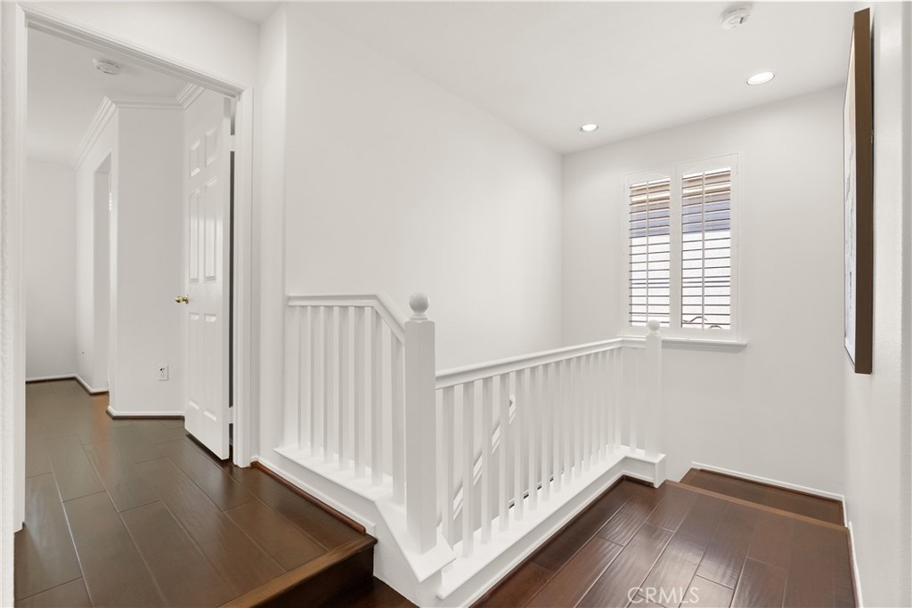 Upstairs, a bright and airy landing with rich wood flooring creates an inviting transition to the home's private bedroom - 15 Poppyfield, Rancho Santa Margarita CA 92688 - photo 16