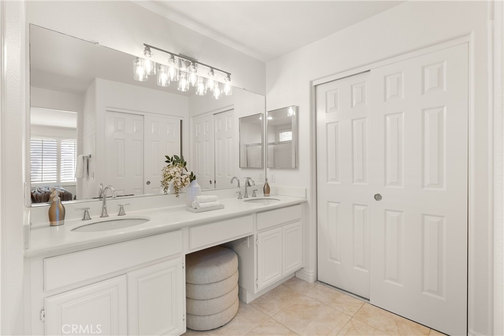 The spacious primary bathroom features a dual sink vanity with expansive counter space, oversized mirrors, abundant stor - 15 Poppyfield, Rancho Santa Margarita CA 92688 - photo 19