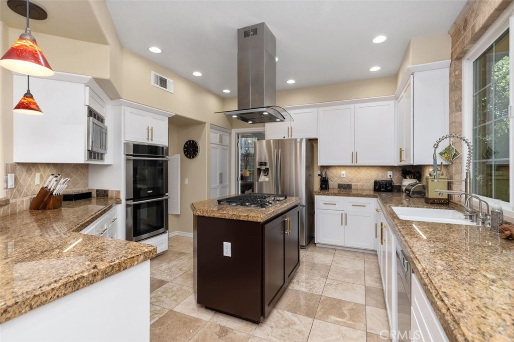 The remodeled chef's kitchen features granite countertops, stainless steel appliances, and a 5-burner gas cooktop island - 21792 Hermosa Lane, Rancho Santa Margarita CA 92679 - photo 11