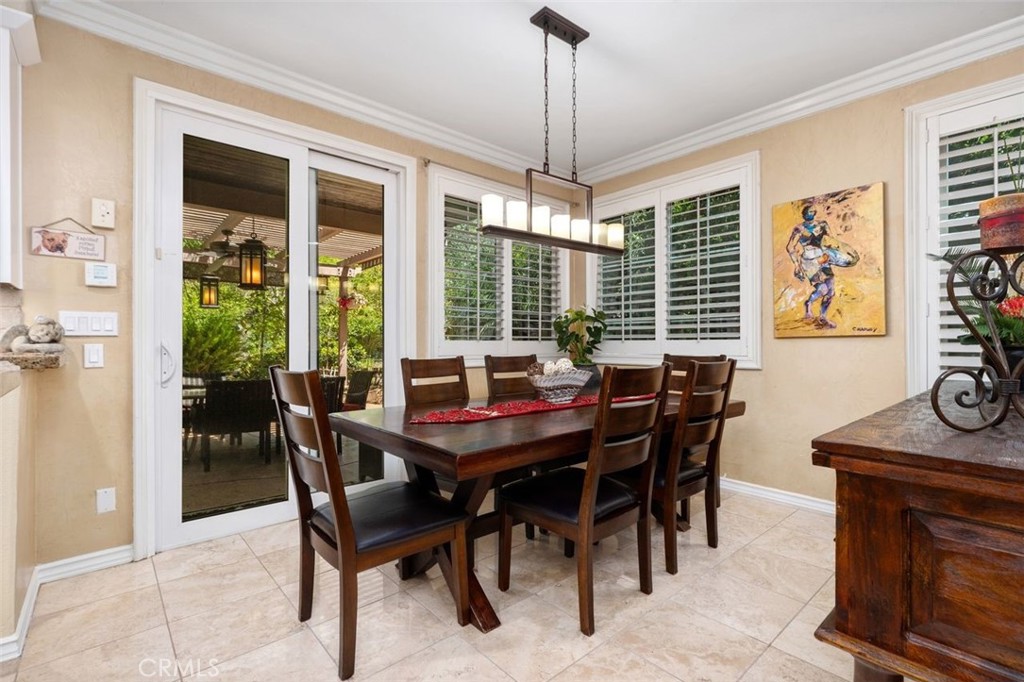 The bright and airy casual dining area features crown molding, travertine tile floors, plantation shutters, and a stylis - 21792 Hermosa Lane, Rancho Santa Margarita CA 92679 - photo 15