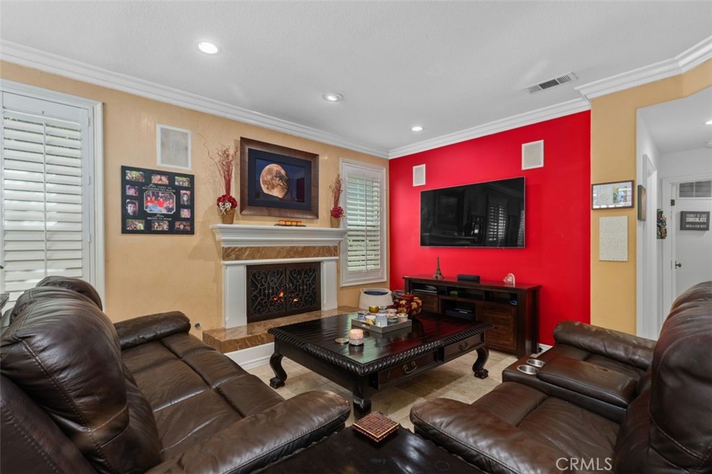 The inviting family room features a classic fireplace with decorative surround, crown molding, recessed lighting, planta - 21792 Hermosa Lane, Rancho Santa Margarita CA 92679 - photo 17