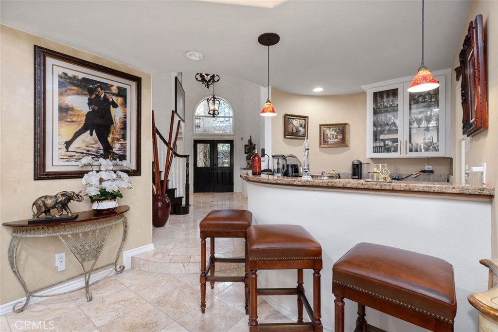 The granite topped bar with pendant lighting and glass front cabinetry anchors the family room and offers a direct sight - 21792 Hermosa Lane, Rancho Santa Margarita CA 92679 - photo 19