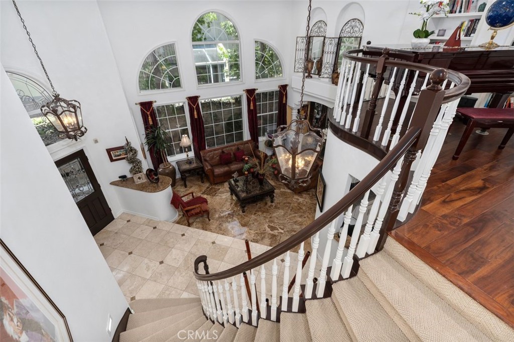The sweeping staircase makes a stunning architectural statement as it curves gracefully from the upper loft down to the - 21792 Hermosa Lane, Rancho Santa Margarita CA 92679 - photo 24