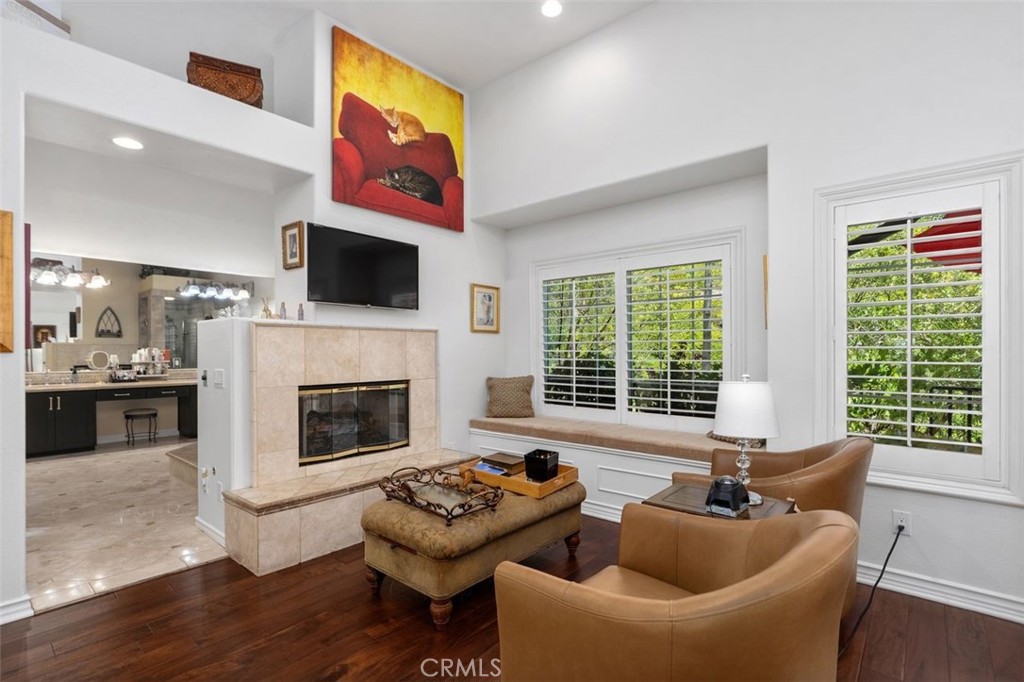 The primary suite sitting area features warm hardwood floors, a two sided fireplace with travertine surround, a built in - 21792 Hermosa Lane, Rancho Santa Margarita CA 92679 - photo 27
