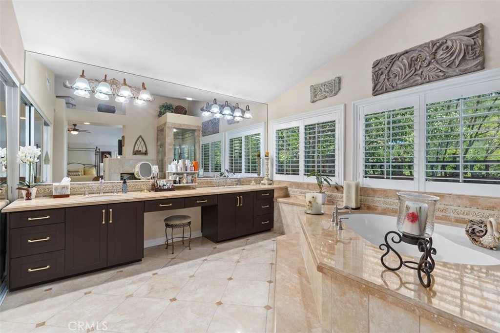 The expansive primary bathroom features a generous dual sink travertine vanity with dark cabinetry and gold hardware, an - 21792 Hermosa Lane, Rancho Santa Margarita CA 92679 - photo 29