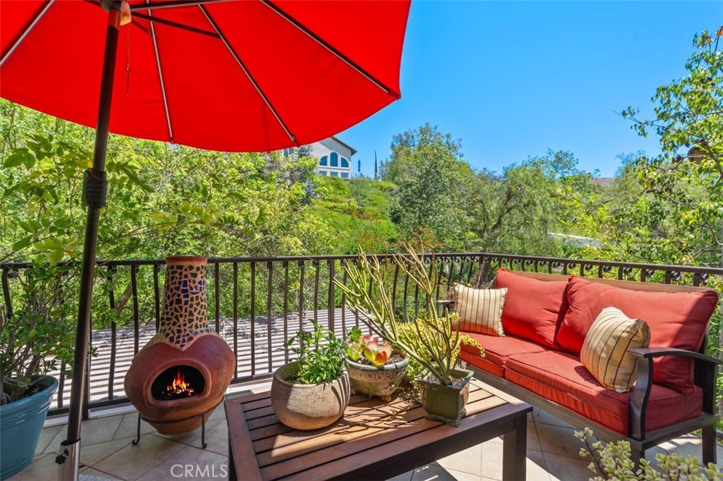 The private balcony off the primary suite offers serene treetop and hillside views, with ample space for outdoor seating - 21792 Hermosa Lane, Rancho Santa Margarita CA 92679 - photo 30