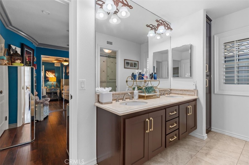 The Jack and Jill bathroom serving the upper level bedrooms features a dual sink travertine vanity, dark cabinetry with - 21792 Hermosa Lane, Rancho Santa Margarita CA 92679 - photo 34
