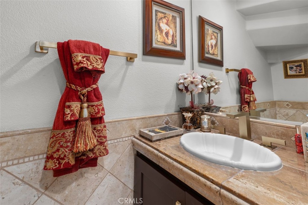 The powder bath impresses with a travertine tile surround, granite vanity countertop, and brushed gold hardware accents. - 21792 Hermosa Lane, Rancho Santa Margarita CA 92679 - photo 36