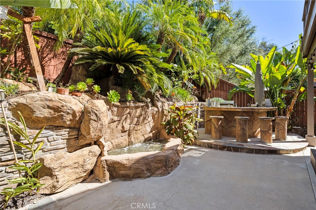 The backyard is surrounded by lush landscaping and features a built-in BBQ area with seating, a fire pit gathering area, - 30 Acanthus, Rancho Santa Margarita CA 92688 - photo 34
