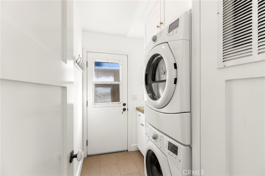 Laundry room with stackable washer/dryer and storage. Door opens up to outdoor shower - 1880 N El Camino Real #14, San Clemente CA 92672 - photo 19