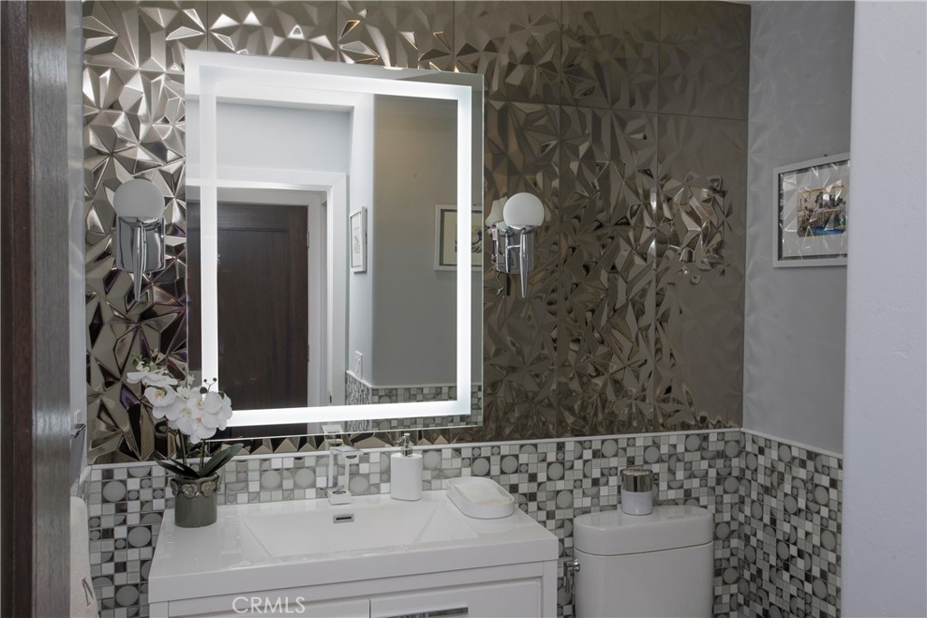The striking powder room showcases a custom metallic feature wall, designer lighting, and a sleek contemporary vanity, c - 3 Via Pasa, San Clemente CA 92673 - photo 13