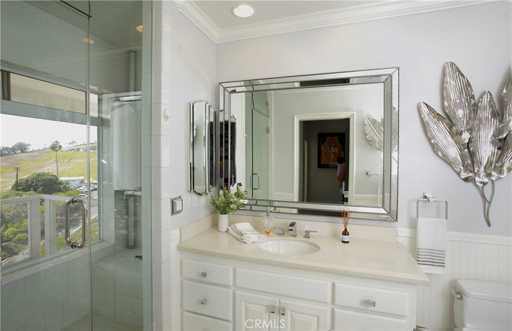 A beautifully appointed guest bathroom features a glass-enclosed walk-in shower, elegant finishes, and abundant natural - 3 Via Pasa, San Clemente CA 92673 - photo 25