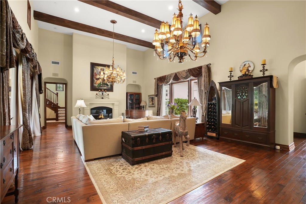 Dramatic great room with soaring ceilings, exposed wood beams, rich hardwood flooring, and elegant architectural details - 27532 Calle De La Rosa, San Juan Capistrano CA 92675 - photo 5