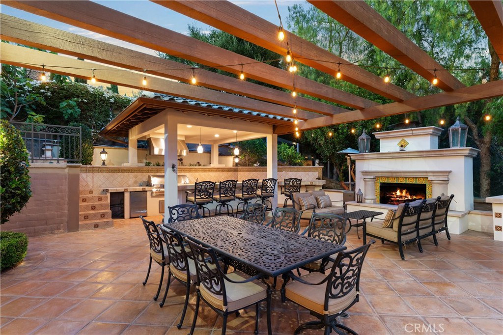 Expansive outdoor entertaining space featuring a fireplace, built-in BBQ, bar seating, and multiple gathering areas. - 27532 Calle De La Rosa, San Juan Capistrano CA 92675 - photo 8