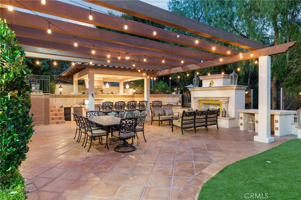 Expansive outdoor entertaining space featuring a fireplace, built-in BBQ, bar seating, and multiple gathering areas. - 27532 Calle De La Rosa, San Juan Capistrano CA 92675 - photo 9