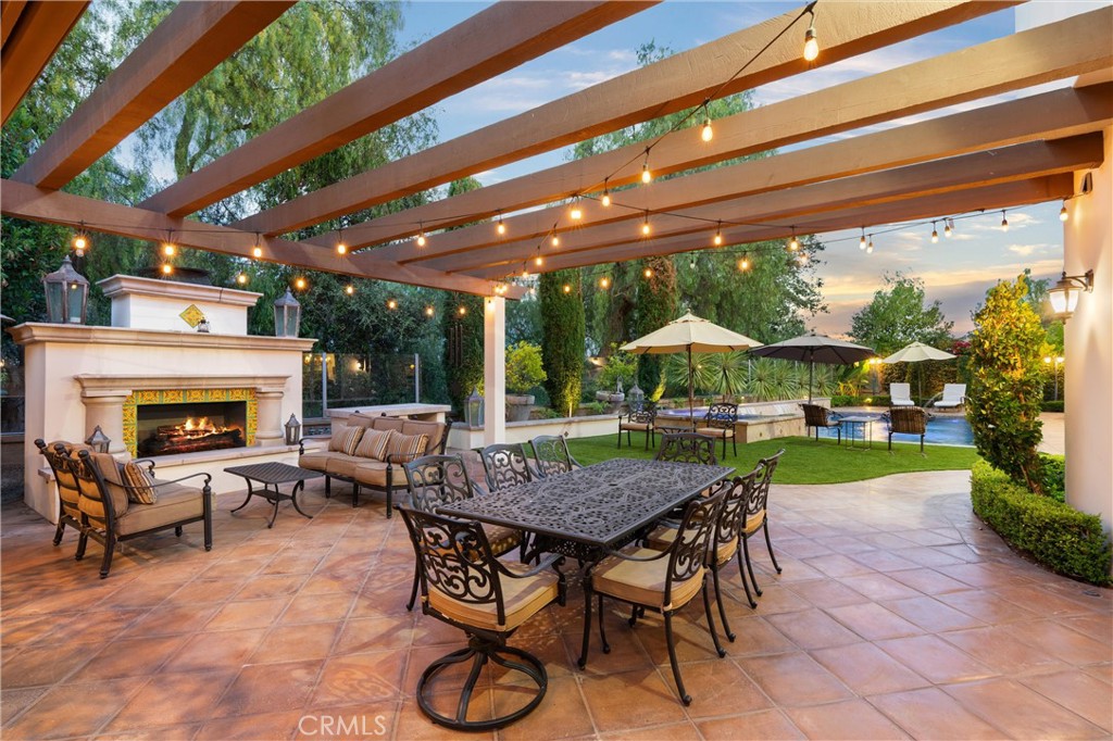 Expansive outdoor entertaining space featuring a fireplace, built-in BBQ, bar seating, and multiple gathering areas. - 27532 Calle De La Rosa, San Juan Capistrano CA 92675 - photo 10