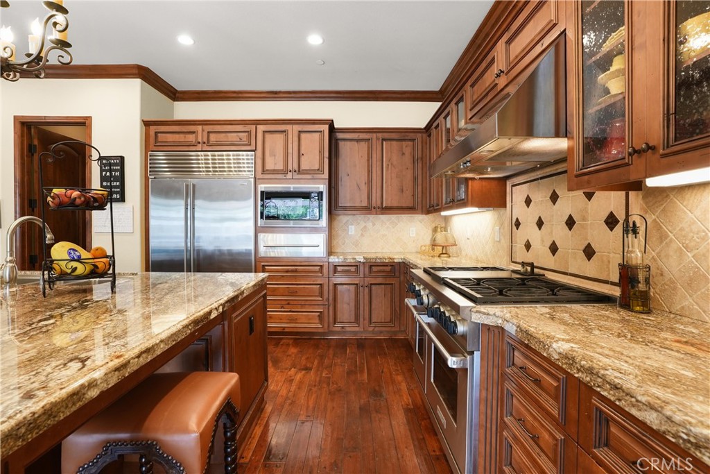 Gourmet kitchen featuring premium Sub-Zero refrigeration, Wolf range, expansive granite center island with seating, and - 27532 Calle De La Rosa, San Juan Capistrano CA 92675 - photo 23