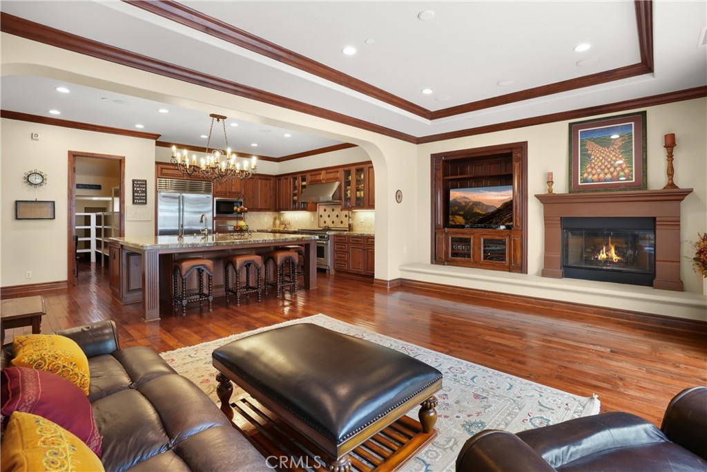 Open-concept family room with custom built-in media center, fireplace, and seamless connection to the kitchen. - 27532 Calle De La Rosa, San Juan Capistrano CA 92675 - photo 30