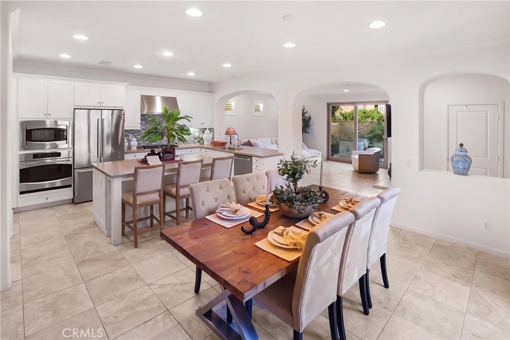 Open-concept kitchen and dining area featuring white cabinetry, stainless steel appliances, generous counter seating, re - 28242 Camino Del Rio, San Juan Capistrano CA 92675 - photo 8
