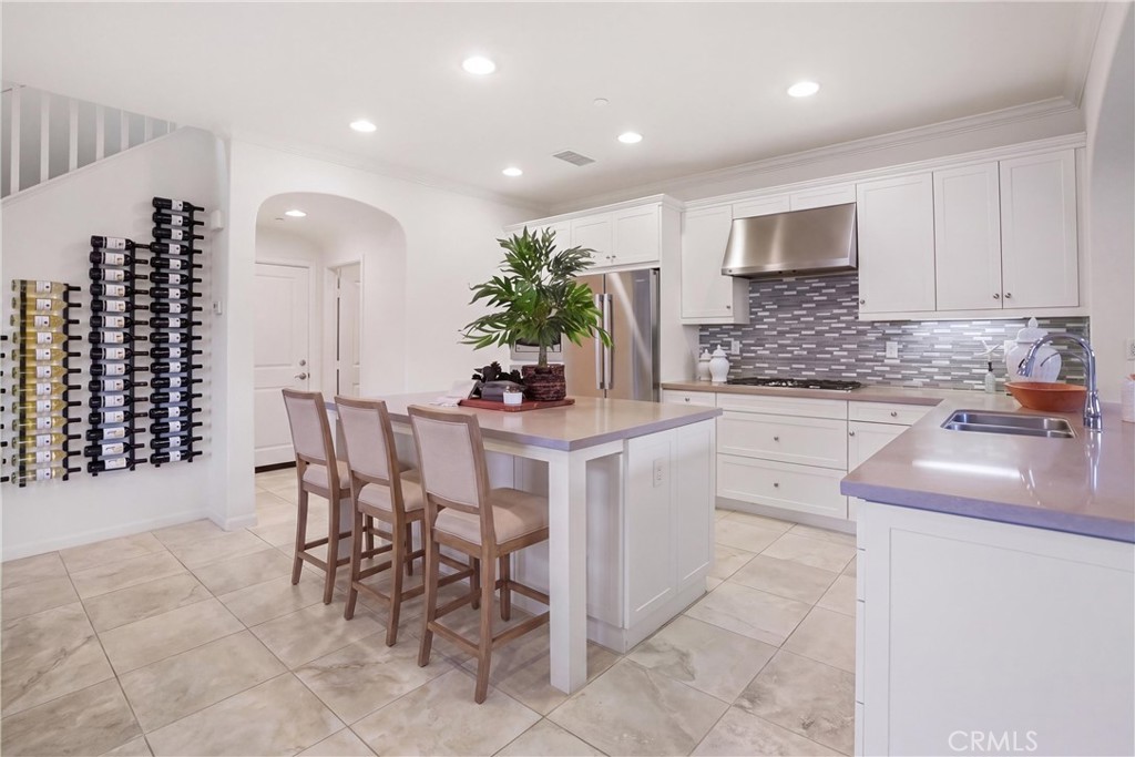 Spacious kitchen showcasing a large center island, white cabinetry, stainless steel appliances, and ample workspace. - 28242 Camino Del Rio, San Juan Capistrano CA 92675 - photo 9