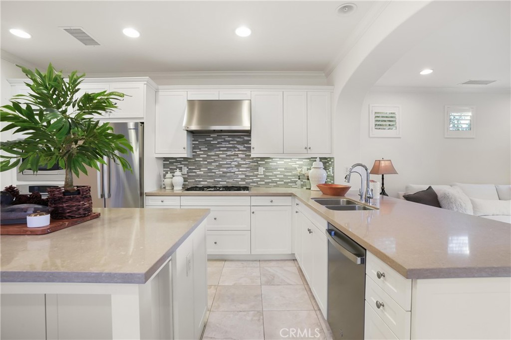Bright kitchen featuring white cabinetry, stainless steel appliances, a gas cooktop with stainless steel hood, mosaic ti - 28242 Camino Del Rio, San Juan Capistrano CA 92675 - photo 12