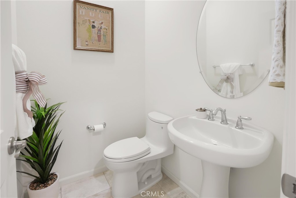 Convenient powder room featuring a pedestal sink, oval mirror, and neutral finishes. - 28242 Camino Del Rio, San Juan Capistrano CA 92675 - photo 16