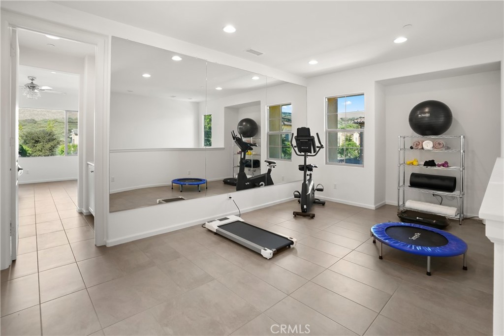 Spacious upstairs loft currently utilized as a home fitness area, featuring a mirrored wall and abundant natural light. - 28242 Camino Del Rio, San Juan Capistrano CA 92675 - photo 20