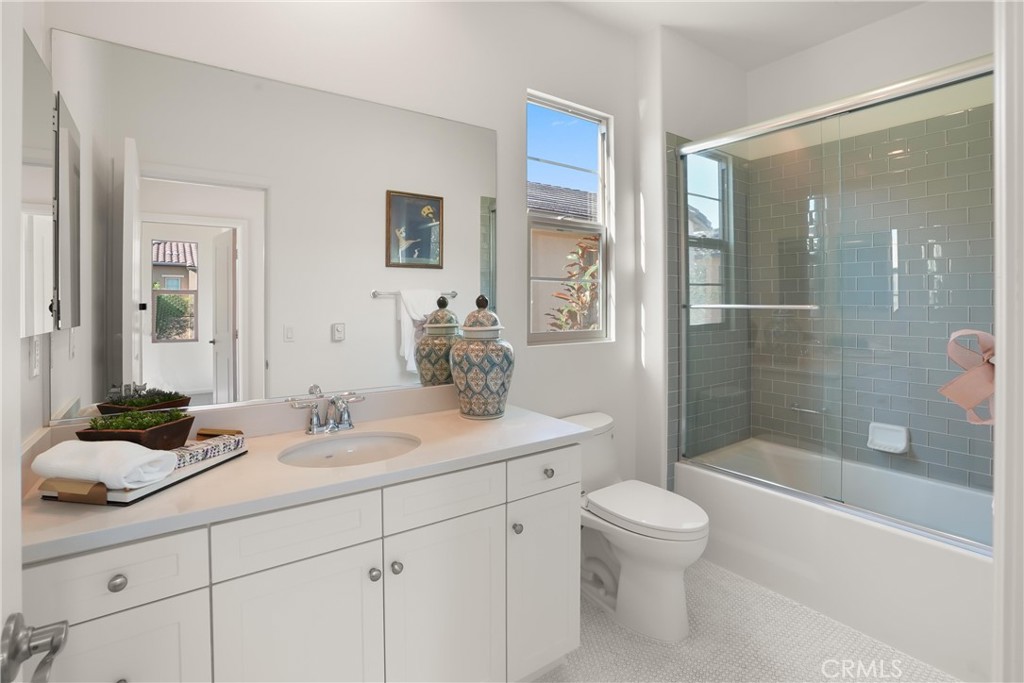 Full bathroom featuring a spacious vanity, tub and shower combination with glass enclosure, and abundant natural light. - 28242 Camino Del Rio, San Juan Capistrano CA 92675 - photo 23