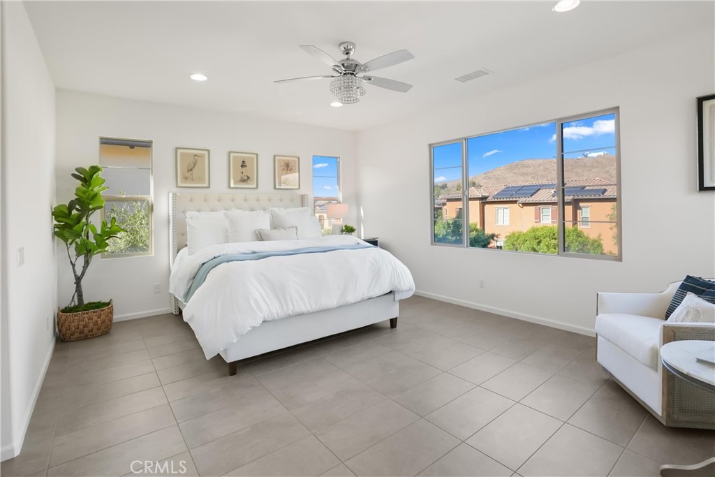 Spacious primary bedroom filled with natural light and featuring expansive windows with hillside views. - 28242 Camino Del Rio, San Juan Capistrano CA 92675 - photo 27