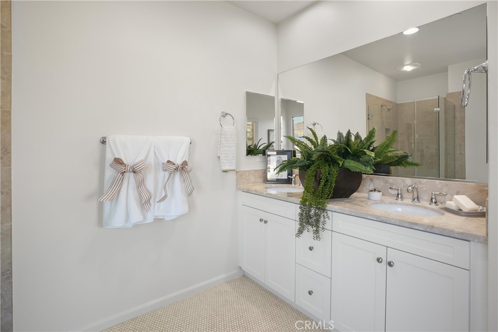 Primary bathroom with dual sinks, generous vanity storage, and an expansive wall mirror. - 28242 Camino Del Rio, San Juan Capistrano CA 92675 - photo 31