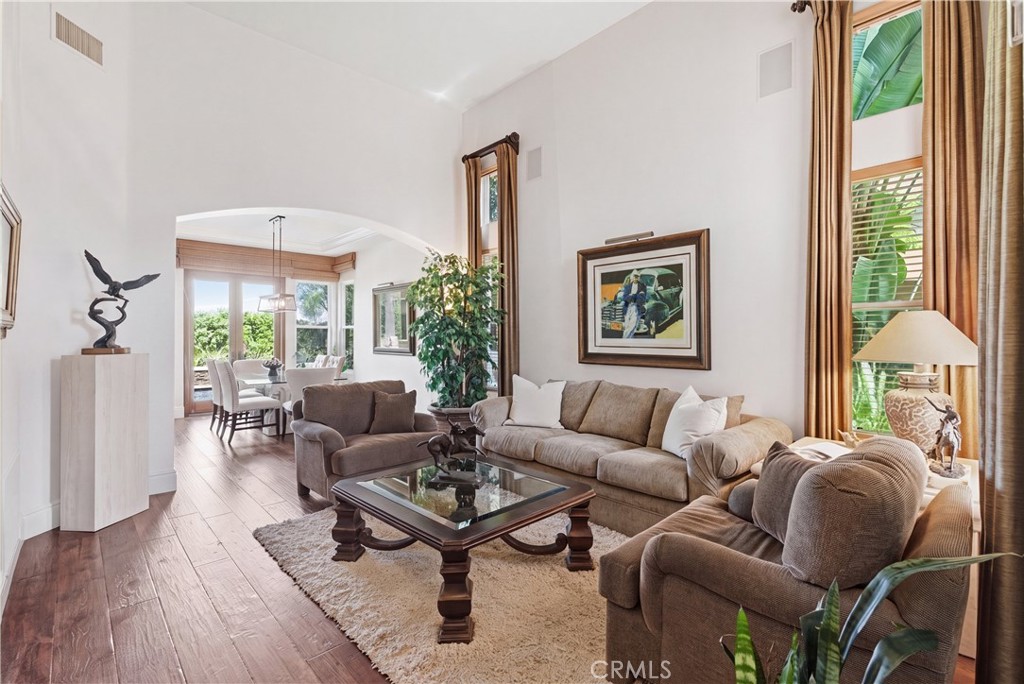 Light-filled living area with soaring ceilings, expansive windows, and rich wood flooring creating an inviting atmospher - 31251 Calle Bolero, San Juan Capistrano CA 92675 - photo 5
