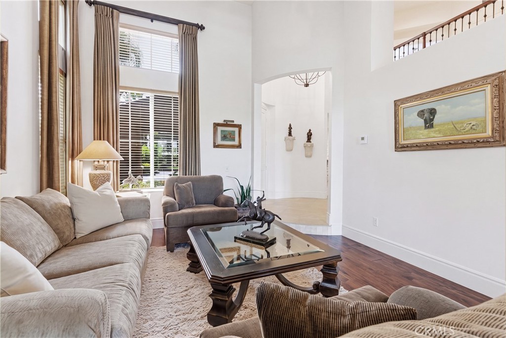 Light-filled living area with soaring ceilings, expansive windows, and rich wood flooring creating an inviting atmospher - 31251 Calle Bolero, San Juan Capistrano CA 92675 - photo 6