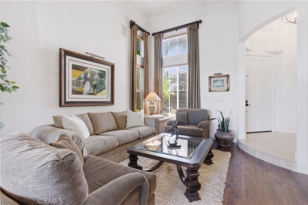 Light-filled living area with soaring ceilings, expansive windows, and rich wood flooring creating an inviting atmospher - 31251 Calle Bolero, San Juan Capistrano CA 92675 - photo 7
