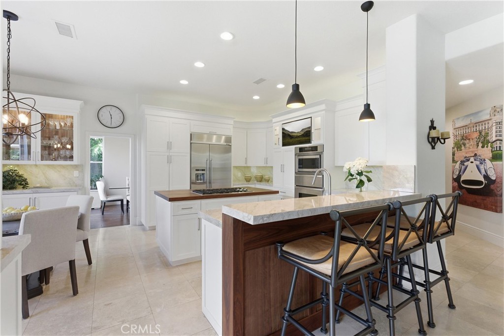 Remodeled kitchen featuring custom cabinetry, Taj Mahal quartzite countertops, stainless steel appliances, and a center - 31251 Calle Bolero, San Juan Capistrano CA 92675 - photo 13