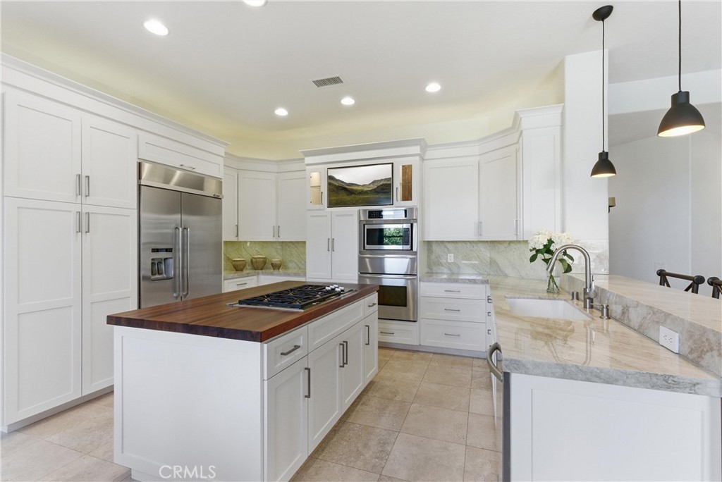 Remodeled kitchen featuring custom cabinetry, Taj Mahal quartzite countertops, stainless steel appliances, and a center - 31251 Calle Bolero, San Juan Capistrano CA 92675 - photo 14